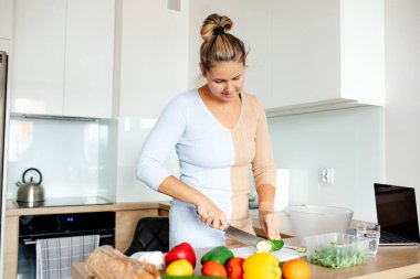 Beyaz, modern mutfakta güzel bir kadın salata için taze sebze keser. Evde yemek pişirmek. Sağlıklı ve lezzetli yemekler. Yemekte vitamin var. Ev hayatı. Doğru yaşam biçimi. 