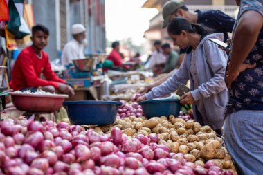Goa, Hindistan, Şubat 2023. Yakın plan tezgahlar dolusu taze sebze patatesler, mavi plastik havzalı kırmızı soğanlar satıcılar ve alıcılar arasında Hindistan 'ın yerel pazarında satılıyor..