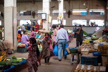 Goa, Hindistan, Şubat 2023. Kapalı Hint geleneksel pazarında farklı insanlardan oluşan bir grup alışveriş yapıyor çeşitli taze sebzeler alıyor meyveler, organik gıda ürünleri alıp tezgahlara bakıyor..