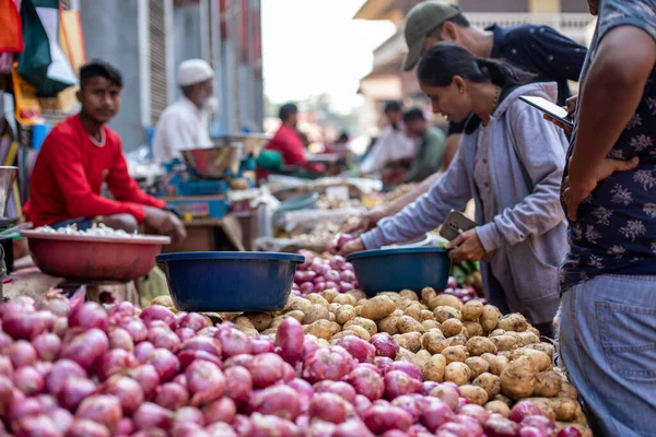 stock image Goa, India, February 2023. Close-up of stalls full of fresh vegetables potatoes, red onions with blue plastic basins for sale at Indian outdoor local street market bazaar between sellers and buyers.