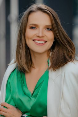 Güzel başarılı iş kadınının, şirket çalışanının, müdürün, ceketli ve yeşil bluzlu şirket patronunun kamera karşısında gülümseyen yüzünün yakın plan portresi. Kariyer. Şirketlerin çalışanları.. 