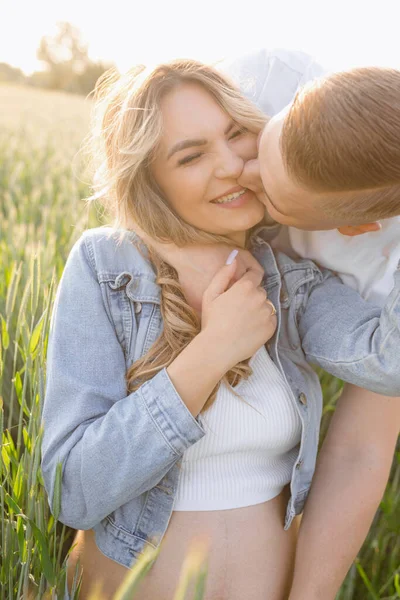 快乐的时刻穿着短柔道的怀孕的金发孕妇的画像 夏天的一天 她被丈夫拥抱着亲吻 家庭关系 积极的情绪 自然能源 — 图库照片