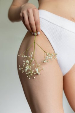 Vurgu, beyaz çingenenin narin çiçeğinin kadın vücudunun kusursuz bronzlaşmış sağlıklı cildine bastırılmasıdır. Gençlik ve güzellik. Fitness ve diyet. Vücut ve cilt bakımı. Cilt için doğal kozmetikler. 