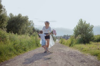 Eğleniyorlar ve yaz gününün tadını çıkarıyorlar ve annelerinin doğum günü, kırsal yolda anne ve oğul, birlikte mutlular. Bekar ebeveynler. Olumlu duygular. Mutlu bir çocukluk. Aile ilişkileri. Dokunaklı anlar.