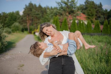 Birlikte vakit geçirmek, kırsal yolda sıcak bir yaz günü yürürken anne ve oğluna sarılmak. Aile ilişkileri. Olumlu duygular. Birlikte mutluyuz. Sevgi ve anlayış. Köyde tatiller. 