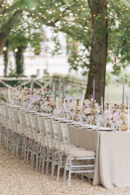Klasik tarzda düğün. Bej renkli doğal tonlarda düğün masası, gül buketleri, eski parktaki klasik şamdanlar. Doğal kumaşlardan yapılmış masa örtüsü, keten.. 