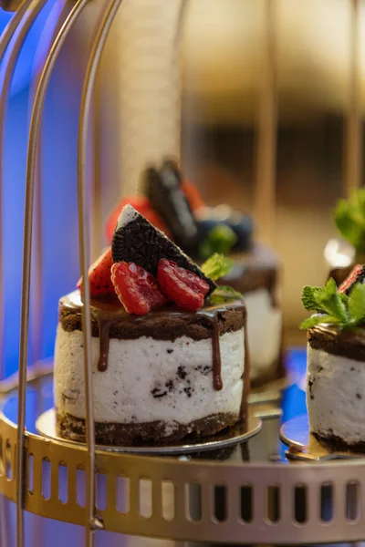 Close-up of delicious dessert, small cake with chocolate, strawberries, whipped cream at wedding event, party, holiday. Enjoying taste. Making cakes to order. Confectionery products. Candy bar.