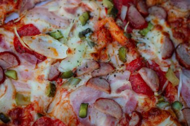 Jambonlu, peynirli, zeytinli ve turşulu yakın plan pizza. Pizza teslimatı İtalyan mutfağının tarifleri. Zevk alıyorum. Fast food. Tatil organizasyonu ve partiler. Pizzacı menüsü için resim. 