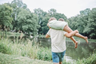 Tanınmayan baba ve kızı yaz günü doğa yürüyüşünden zevk alır, baba kızını omuzunda taşır. Kaygısız çocukluğun kutlu olsun. Uyumlu sevgi dolu bir aile. Bekar bir baba. Babalık.