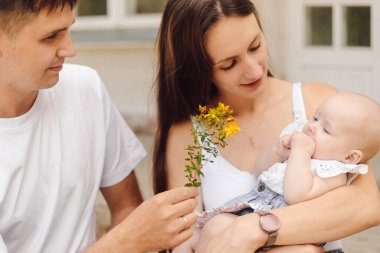 Ebeveyn sevgisi ve şefkat. Küçük kızı olan mutlu çift yaz günü parkta annesinin kollarında. Aile fotoğrafı. Çocukluğun korunması, korunması. Genç bir aileye borç vermek. Aile değerleri. 