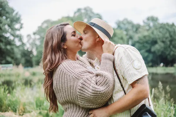 Happy spouses hug and kiss each other on summer day in nature, enjoying moment. Happy together. Harmonious loving happy family. Right relationship. Positive emotions. Family vacation.