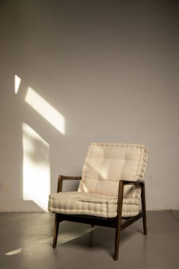 Modern rahat koltuk, bej duvarın karşısında boş bir odada duruyor. İç malzemeler. Minimalizm ve basitlik kavramı. İç dizayn. Tadilat ve ev dekorasyonu. Mobilya mağazası.. 