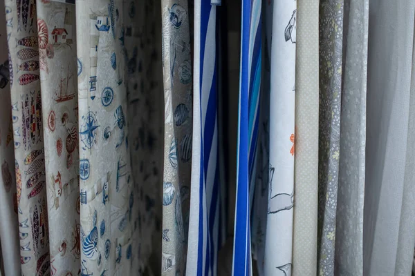 Sewing of home textiles. Fabric store, department in supermarket. Large selection of various cotton fabrics with pattern on shop window. Home improvement and comfort. Natural fabrics for children.