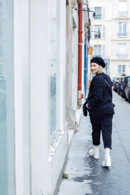 Şehirde dolaşıyordum. Siyah bereli şık bir sarışın, rahat kıyafetler ve bahar günü şehrin sokaklarında yürüyen beyaz çizmeler. Şehir tarzı. Güzellik ve Moda. Turizm ve seyahat.