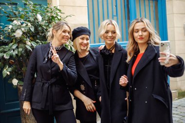 Şık giyinmiş dört çekici genç bayanla birlikte selfie çekiyorlar, bahar günü şehirde dolaşıyorlar. Arkadaşlık ve iletişim. Turizm ve seyahat. Pozitif duygular. 