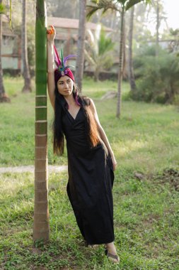 Harmony, kendini arama. Tüylü başlıklı egzotik esmer, güneşin doğuşunu selamlıyor, ağaca yaslanıyor. Ruhani uygulamalar. Dünya ve doğa ile birlik. Esrarengiz. Huzur ve rahatlama.