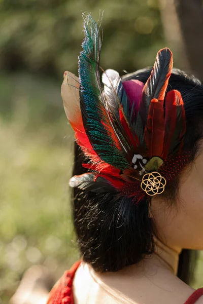 Close-up of headdress made bright feathers stylized by North American Indians on head of unrecognizable woman. Harmony, self-search. Traditions and rituals. Unity with nature. Esotericism.