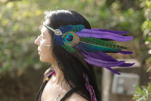 Traditional Indian feather headdress on head of brunette woman with long hair. Ethnic elements. Harmony, self-search. Traditions and rituals. Culture of indigenous peoples of North America.