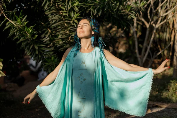 Human energy resources. Beautiful young woman in long turquoise dress performs ceremony of meeting sun. Harmony, self-search. Unity with nature. Morning energy practices. Positive emotions, joy, .