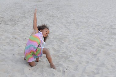 Çocuk yogası. Koyu tenli küçük bir kız kumsalda oturuyor, yaz sabahının erken saatlerinde yoga egzersizi yapıyor. Sağlık ve spor. Hobi olarak. Mutlu bir çocukluk. Çocukların uyumlu gelişimi. 