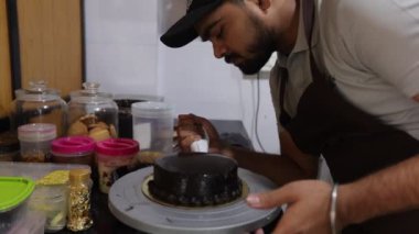 Erkek aşçı, aşçı yemek yapar, pastayı çikolatalı kremayla kaplar. Tatlı tatlılar yapıyorum. Fırın. Yemek kursları. Kendi prodüksiyonum. Pasta siparişi. Zevkin zevki. Küçük bir iş. 4k görüntü