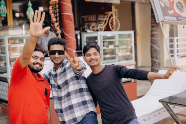 Üç arkadaş kafenin dışında selfie çekiyorlar, güneşli havanın tadını çıkarıyorlar ve iyi vakit geçiriyorlar.