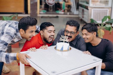 A group of friends is celebrating a birthday outdoors, sharing joyful moments with cake and happiness clipart