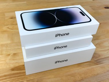 Elma iPhone 'ları tahta masaya istiflenmiş kutularda. iPhone 14 Pro, 12 ve XR.