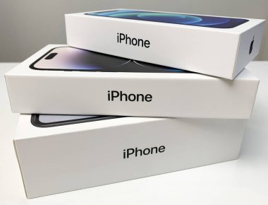 Elma iPhone 'ları beyaz masaya istiflenmiş kutularda. iPhone 14 Pro, 12 ve XR.