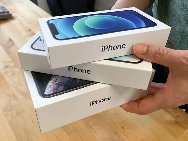 Kutularda bir yığın Apple iPhone tutan bir kadın. iPhone 14 Pro, 12 ve XR.