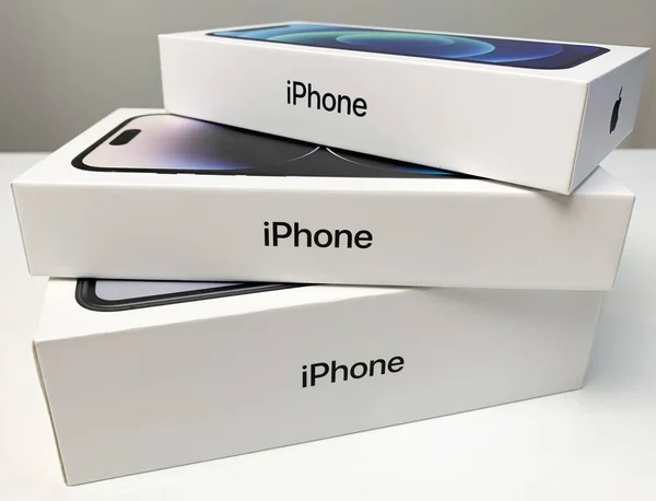 Elma iPhone 'ları beyaz masaya istiflenmiş kutularda. iPhone 14 Pro, 12 ve XR.