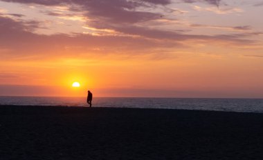 Gün batımında sahilde yürüyen siluetli bir adam. Kimliği belirsiz tek bir adam. Yalnızlık kavramı.
