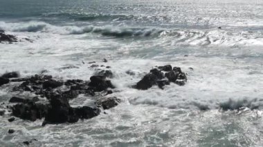 Yavaş çekim dalgaları Matosinhos plajında kayaların üzerinden geçiyor, Portekiz baharda. Geniş açı. Yavaşça sola kaydır.