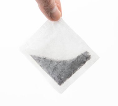 Parmak ve başparmak arasında duran çay poşeti. Beyaz arkaplanda izole.