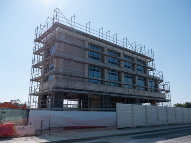 İnşaat halindeki apartmanın dış tarafında iskeleler var. Yeni inşa edilebilir konut.