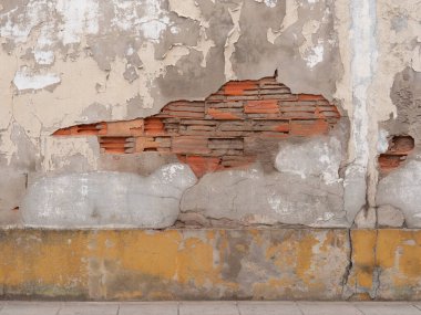 Kırık alçılı eski duvar altında kırmızı tuğla olduğunu gösteriyor. Yıpranmış, grunge arkaplan.