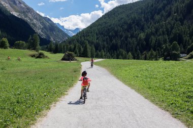 Dağ yolunda dağ bisikleti ve babasıyla gezen bir çocuk..