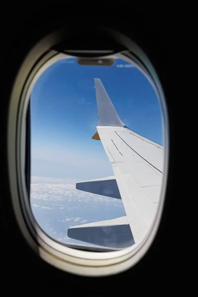 View from Inside an Aircraft: Window of the Cabin, White Airplane Wing and Clouds.