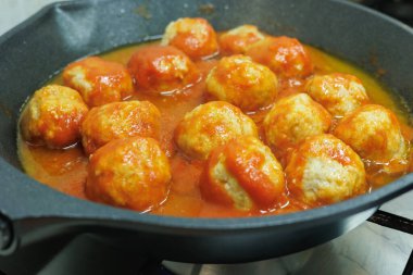 Küçük bir tavada pişirilmiş domates soslu köfte..