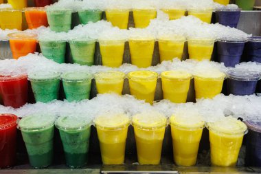 Muz, greyfurt, portakal, kivi aromalı buzlu meyve suyu. Plastik bardakların içinde..