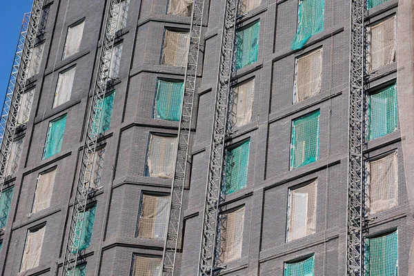 Exterior Facade of a Gray Building under Renovation with Windows with Protective Nets.