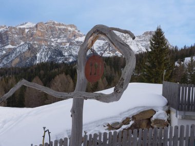 Eğri Ahşap Gövde ve içinde Çatal, Bıçak ve Kaşık ve İtalyan Alp Dağları olan bir Yemek Yeri 'nin Demir Küpü var..