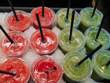 Muz, greyfurt, portakal, kivi aromalı buzlu meyve suyu, içinde samanla plastik bardaklar..