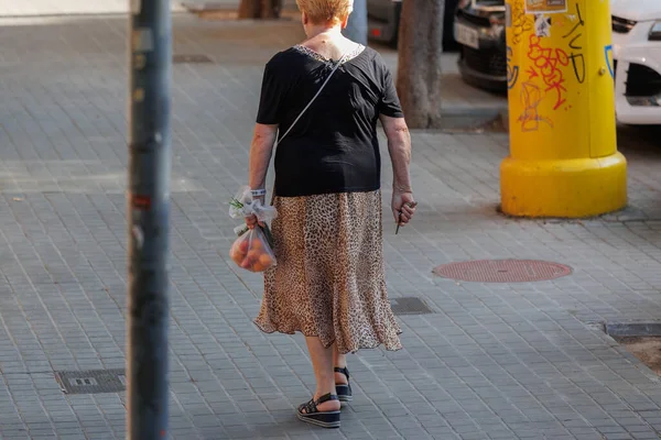 スペイン バルセロナ2022年8月 果物と野菜と家の鍵を持つ2つの小さなショッピングバッグと歩道を歩く女性 — ストック写真