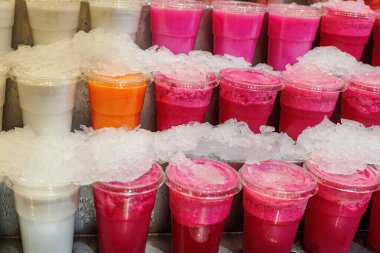 Muz, greyfurt, portakal, kivi aromalı buzlu meyve suyu. Plastik bardakların içinde..