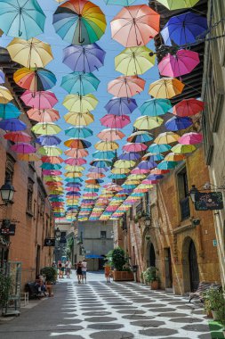 Şemsiyeler askıya alındı ve Poble Espanyol 'un bir caddesinde Renkli Şemsiyeler Çatı' sını oluşturmak için birleşti, Barselona, İspanya.