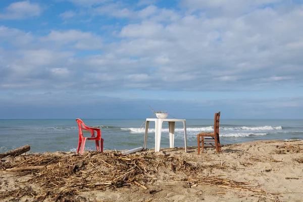 stock image Two Chairs and a Plastic Side Table with a Colander Resting on top with Wood Remains.