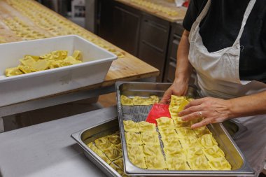 Uzun tahta bir masa üzerinde İtalyan Doldurulmuş Tortelli hazırlanıyor..