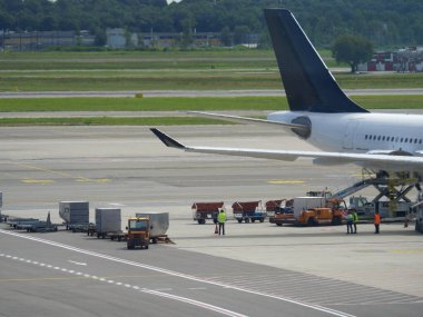 İçinde yemek bulunan metal tramvaylar pist yakınındaki Uçuş Hattı uçağına yüklenmeye hazır..
