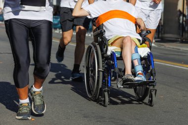 Spor Maratonu sırasında Tekerlekli sandalyedeki Atletler ve Oğlan.